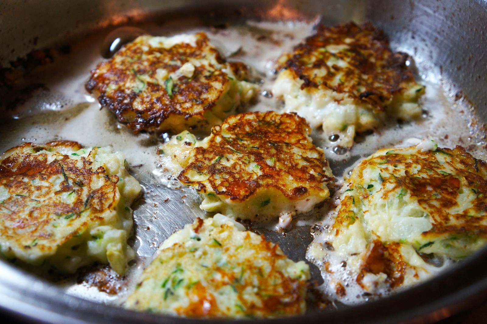 Petites galettes de courgette dorées parsemées de fines herbes et de parmesan.